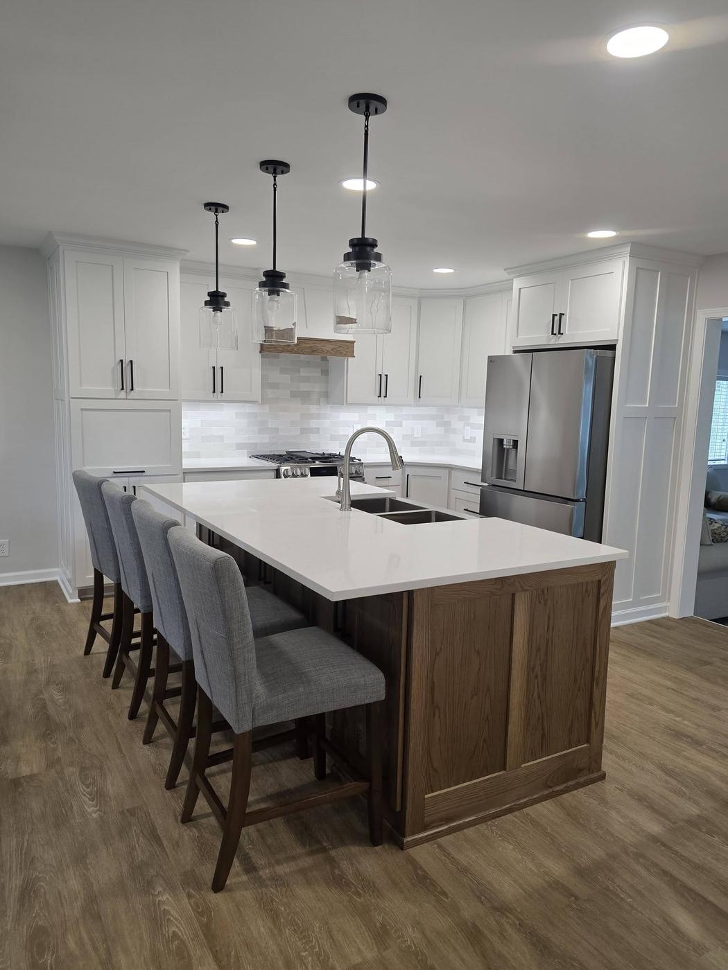 A finished white shaker kitchen with an oak island and grey stacked-tile backsplash